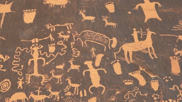panning shot of an american indian art petroglyph of a hunting scene on newspaper rock at canyonlands national park, utah