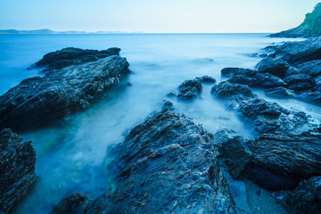 Silky sea with rock on coast and blue sky