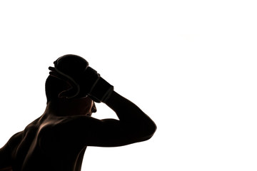The guy sportsman of martial arts covered his face with his gloved hand. A boxer with a bare torso strikes his elbow or protects his head. Sports theme. Black silhouette on white background. Isolated.