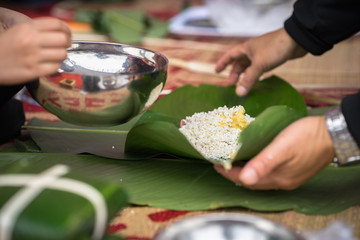 The son learning to make Chung cake by hands with his father closeup, Chung cake is the most important traditional Vietnamese lunar New Year (Tet) food.