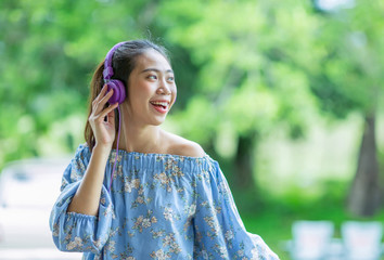 Young smiling asian woman listening to music with headphones