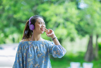 smilling asian woman listening to music with headphone