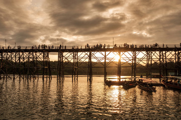 Fototapeta premium Ancient wooden bridge with tourists travel at sunset