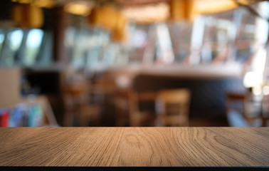 Naklejka na ściany i meble Empty wooden table in front of abstract blurred background of coffee shop . can be used for display or montage your products.Mock up for display of product.