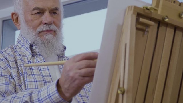 Senior man draws picture enjoying the process of drawing