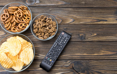 chips, crackers, snacks, TV remote control on the background of a wooden table. free time. leisure.