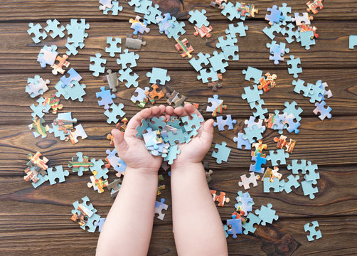 puzzles on a wooden background. puzzles in the hands of a child. logical game. preschool education