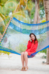 Young woman in red dress enjoying a sunny day in the hammock