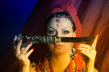 a woman in a red oriental suit with a dagger in her hands