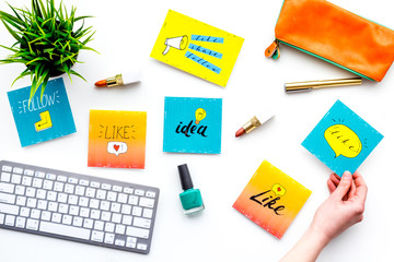 Work desk of beauty blogger with social media icons and cosmetics on white background top view