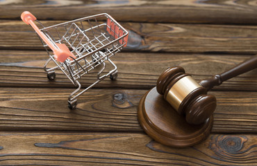 hammer of the judge, a trolley from a supermarket on a wooden background. consumer rights Protection.