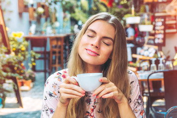 Beautiful woman is enjoying a cup of coffee in the cafe
