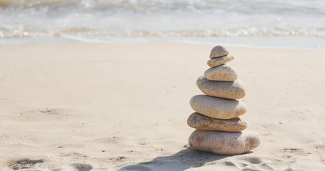 Fototapeta na wymiar Balancing stone tower against morning sea