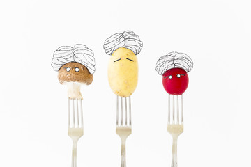 Potato, red radish and mushroom on white background with turban sitting as fakir on top of silver...