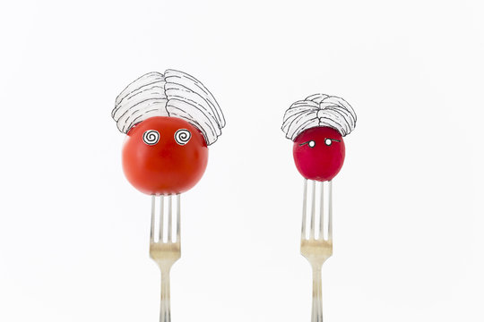 Red tomato and radish on white background with turban sitting as fakir on top of silver forks representing indian food.