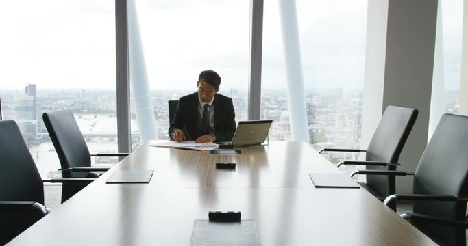4K Successful businessman working alone in boardroom of city office. Slow motion.