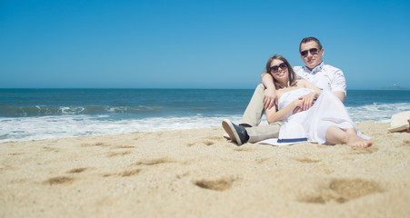 Fototapeta na wymiar Young romantic couple sitting on the beach