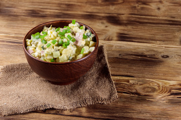 Traditional Russian festive salad Olivier on wooden table