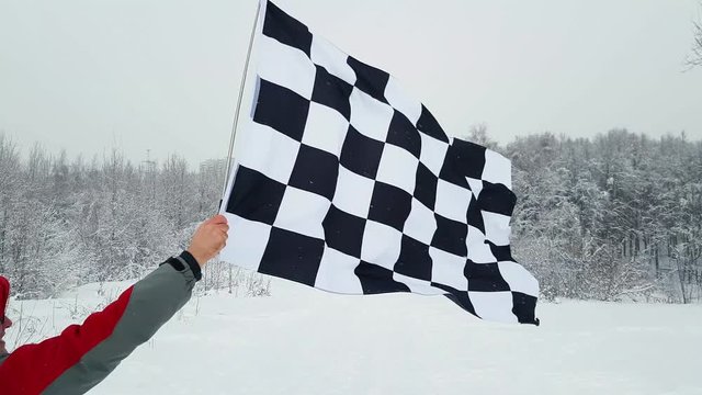 Man waving the finish flag in winter. Back view