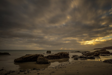 Obraz premium Beach on a Canarian island with dark clouds and big lava mountains at sunset