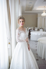 Fototapeta premium Beautiful bride in a wedding dress white interior
