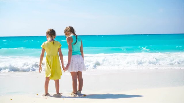 Adorable little girls have a lot of fun on the beach. Two beautiful kids running and splashing in shallow water