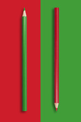 two pencils of green and red on a red and green background, symbolize the opposite