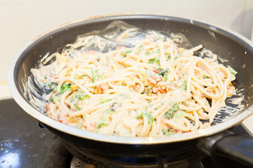 cooking spaghetti carbonara on pan white sauce
