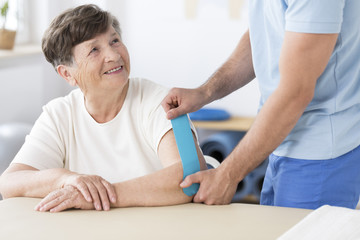 Obraz premium Physiotherapist sticking kinesiotape to woman