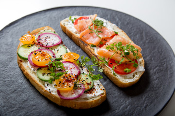 Healthy and tasty toast bread with tomato, radish, salmon fish and cheese on it.