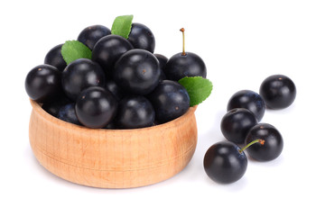 blackthorn berries in wooden bowl with green leaf isolated on white background