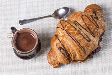 one large swirled puff chocolate croissant with a mug of coffee