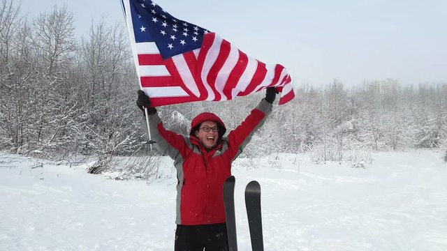 Middle-aged man sport fan waving an American flag in the winter ski slope background