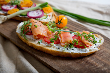 Healthy and tasty toast bread with tomato, radish, salmon fish and cheese on it.