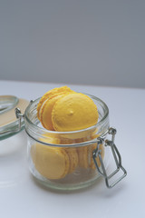 Yellow pastel macaroons in glass jar. French almond cookies