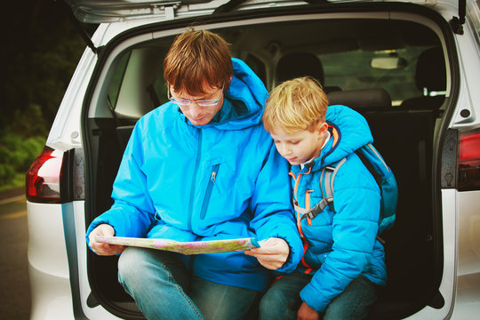 father and son looking at map while travel by car