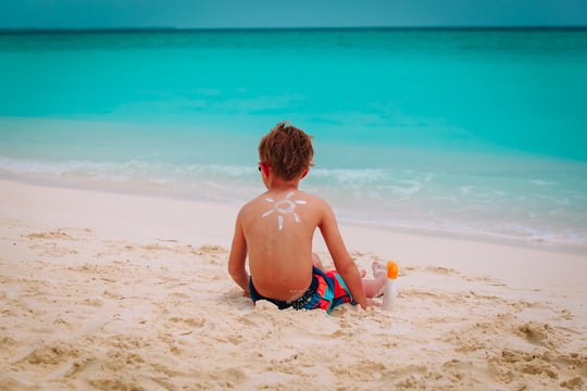 sun protection- little boy with suncream at tropical beach