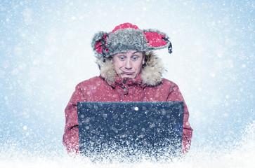 Funny man programmer in red winter clothes with laptop, cold, snow, blizzard