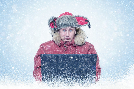 Funny man programmer in red winter clothes with laptop, cold, snow, blizzard