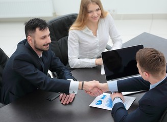 handshake financial partners sitting at the table