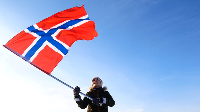 Woman with norway flag on the top point. Succesful winer consept