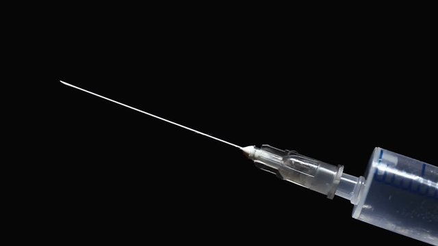 Shaking hand in white sterile glove removes cap of syringe with clear liquid