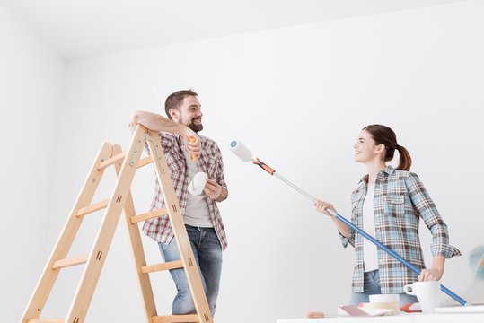 Playful couple painting walls