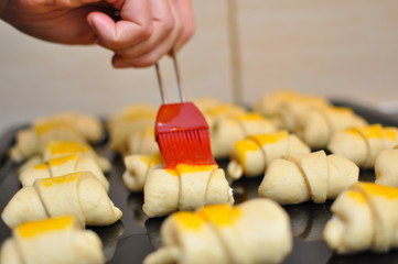 Coating mixed egg yolk on rolls . Making domestic rolls with cheese