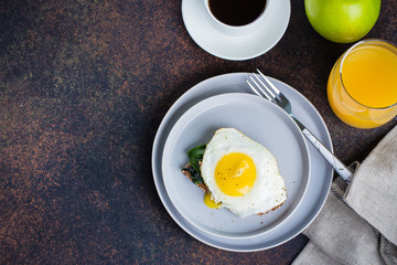 Rye bread toasts with fried spinach and egg with cup of coffee and orange juice on blue table background. Healthy Breakfast Food Concept. Top view with Copy Space