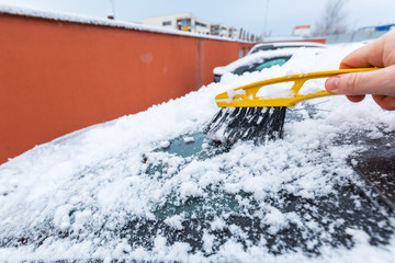 Scraping frozen snow from the car windows