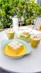 Saffron and pistachio Tres leches cake and cup of cappuccino with marshmallow topping.