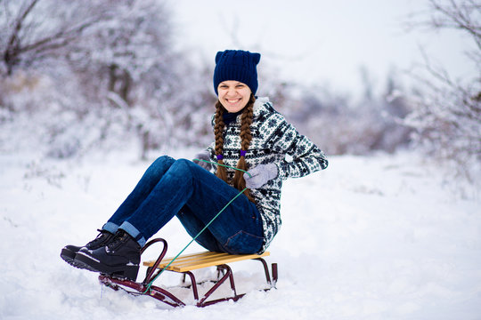 Cheerful young woman having fun on a sleigh in snowy weather