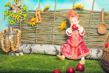 little girl in Russian national costume, with apples, samovar and birch dryers 