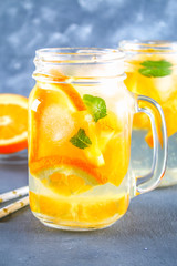 Fototapeta na wymiar Orange detox water in mason jars on a gray concrete background. Healthy food, drinks.